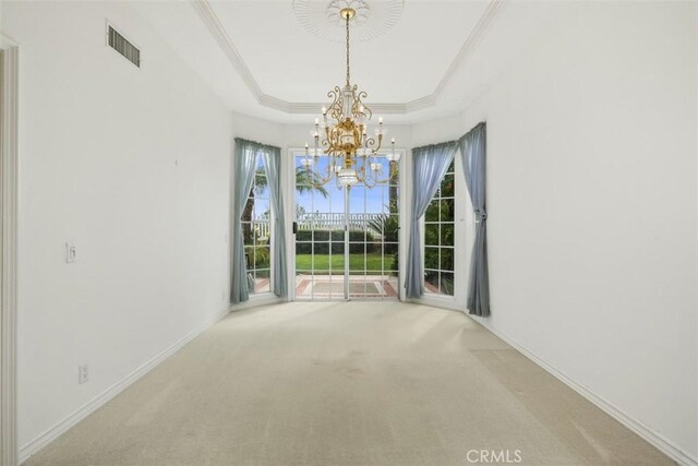 unfurnished dining area featuring a chandelier, a tray ceiling, carpet flooring, baseboards, and ornamental molding