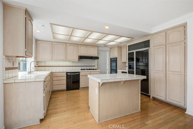 kitchen featuring black appliances, tile countertops, under cabinet range hood, light wood-type flooring, and recessed lighting
