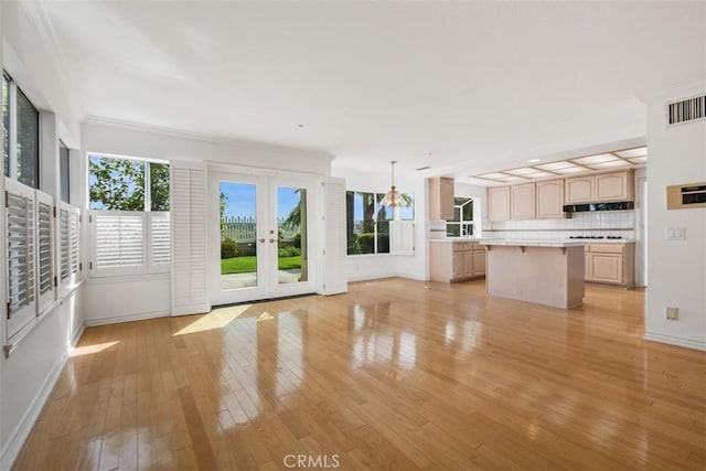 unfurnished living room featuring baseboards, french doors, and light wood-style flooring
