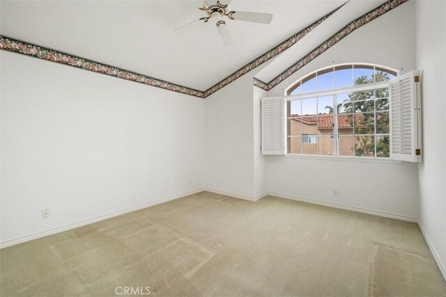 unfurnished room featuring carpet, a ceiling fan, vaulted ceiling, and baseboards