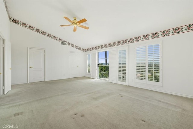 carpeted empty room with ceiling fan, vaulted ceiling, and baseboards