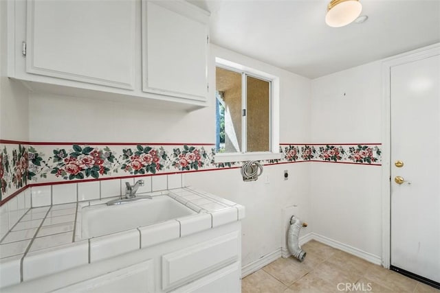 washroom featuring electric dryer hookup, cabinet space, baseboards, and light tile patterned floors
