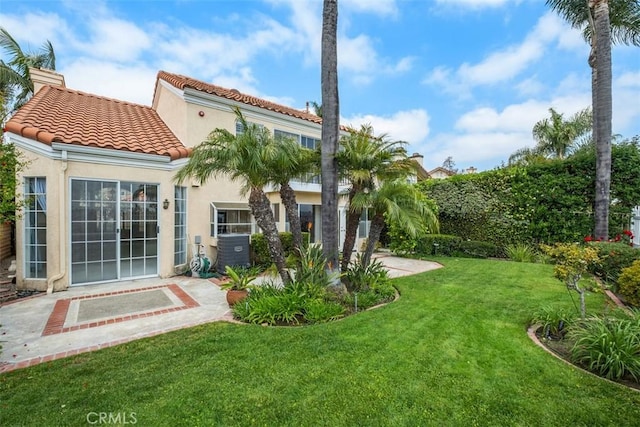 back of property with a yard, stucco siding, a tiled roof, and a patio area