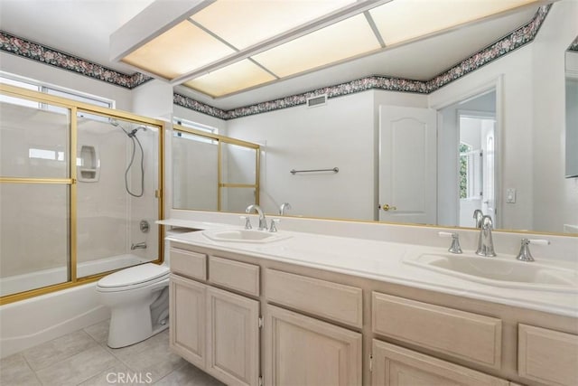 full bath with combined bath / shower with glass door, tile patterned flooring, double vanity, toilet, and plenty of natural light
