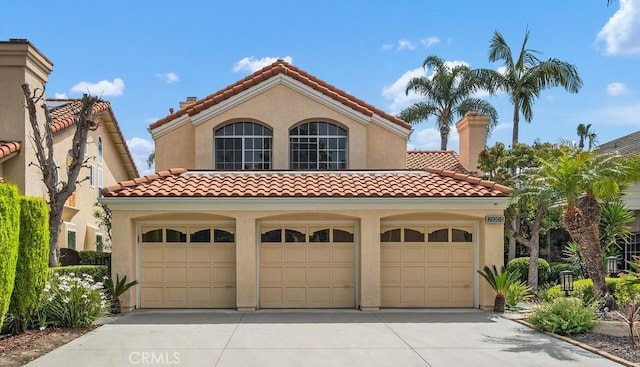mediterranean / spanish home with concrete driveway, a garage, stucco siding, and a tile roof