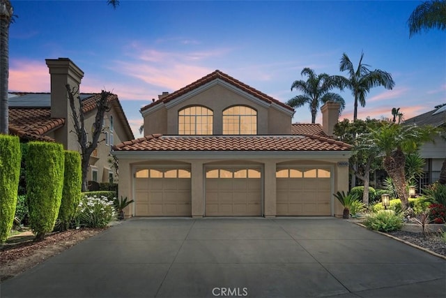 mediterranean / spanish house with concrete driveway, a tiled roof, and stucco siding