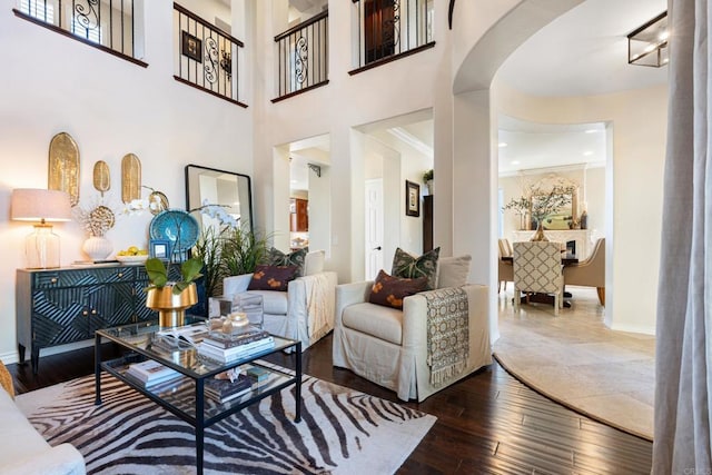 living area with baseboards, arched walkways, and hardwood / wood-style flooring