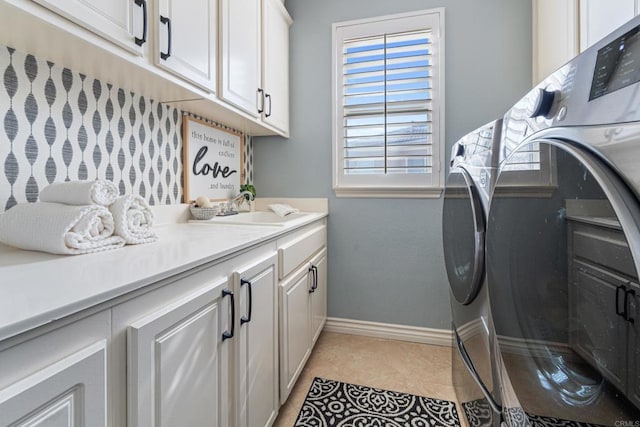 laundry area featuring washing machine and dryer, a sink, cabinet space, baseboards, and light tile patterned flooring
