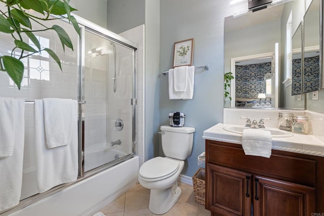 full bathroom with toilet, tile patterned floors, vanity, and bath / shower combo with glass door
