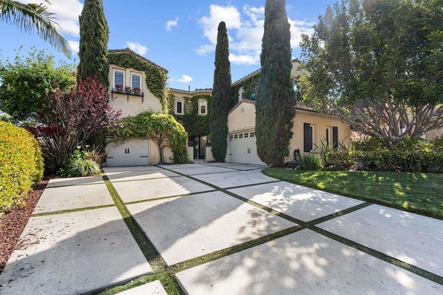 mediterranean / spanish house featuring a front lawn, stucco siding, driveway, and a garage