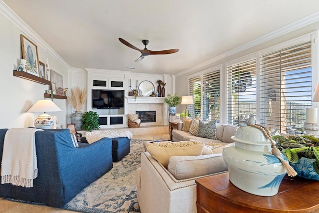 living area featuring a ceiling fan, ornamental molding, and a fireplace with raised hearth