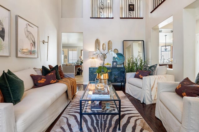 living area featuring a notable chandelier, a high ceiling, and wood finished floors