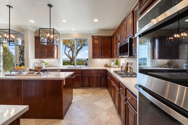 kitchen with a sink, a chandelier, light countertops, tasteful backsplash, and appliances with stainless steel finishes