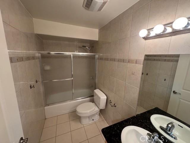 bathroom featuring tile patterned floors, toilet, visible vents, and tile walls
