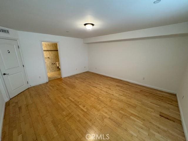 empty room with light wood-style floors, visible vents, and baseboards