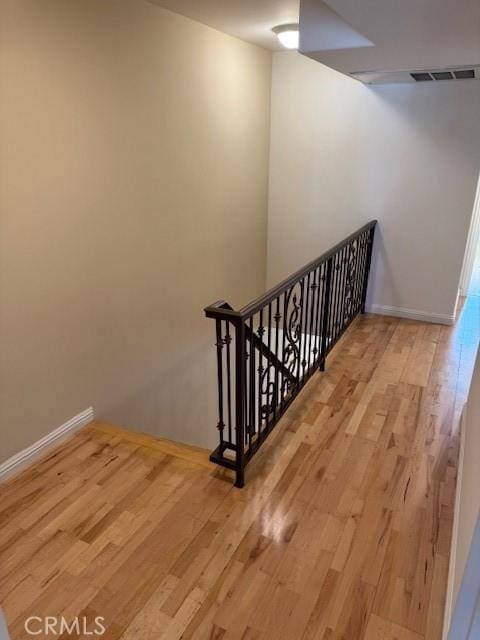 stairs with baseboards, visible vents, and wood finished floors