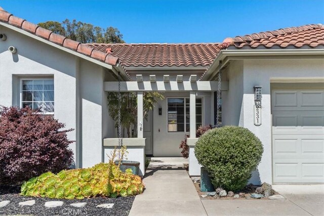2331 Humboldt St, Los Osos, CA 93402 - doorway to property featuring an attached garage, a tiled roof, and stucco siding