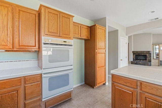2331 Humboldt St, Los Osos, CA 93402 - kitchen featuring double oven, tile countertops, light tile patterned floors, and brown cabinets