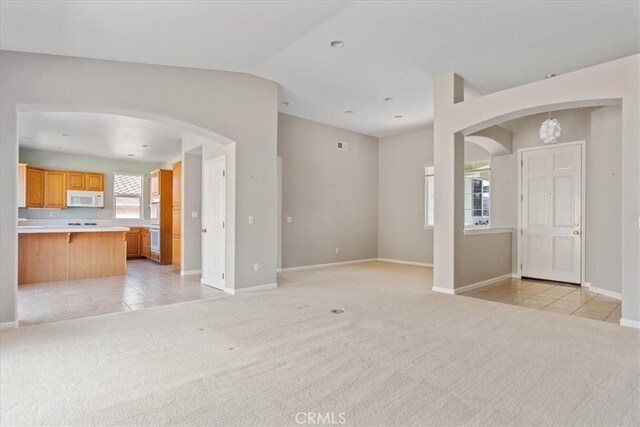 2331 Humboldt St, Los Osos, CA 93402 - unfurnished living room with arched walkways, light carpet, light tile patterned floors, baseboards, and vaulted ceiling