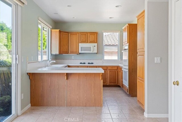 2331 Humboldt St, Los Osos, CA 93402 - kitchen with white appliances, a peninsula, a sink, tile countertops, and baseboards