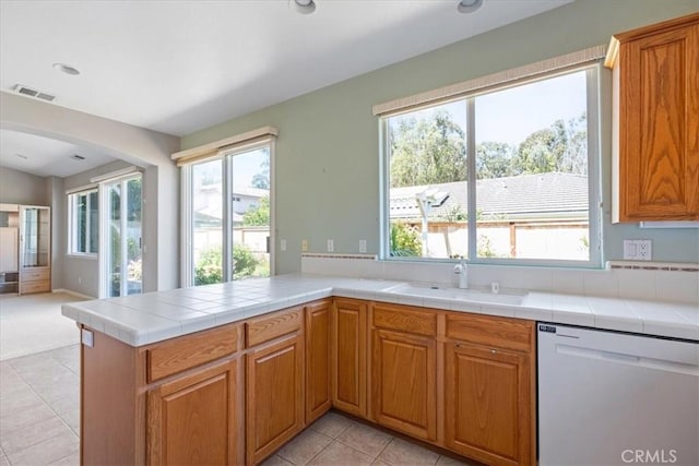 2331 Humboldt St, Los Osos, CA 93402 - kitchen with white dishwasher, a sink, arched walkways, light tile patterned flooring, and brown cabinetry
