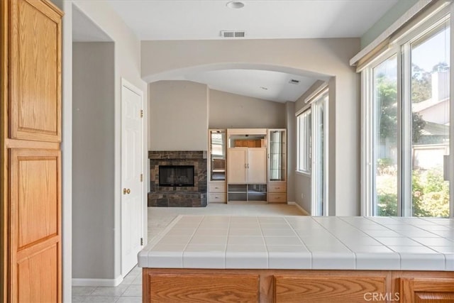 2331 Humboldt St, Los Osos, CA 93402 - unfurnished living room with arched walkways, vaulted ceiling, a stone fireplace, light tile patterned flooring, and baseboards