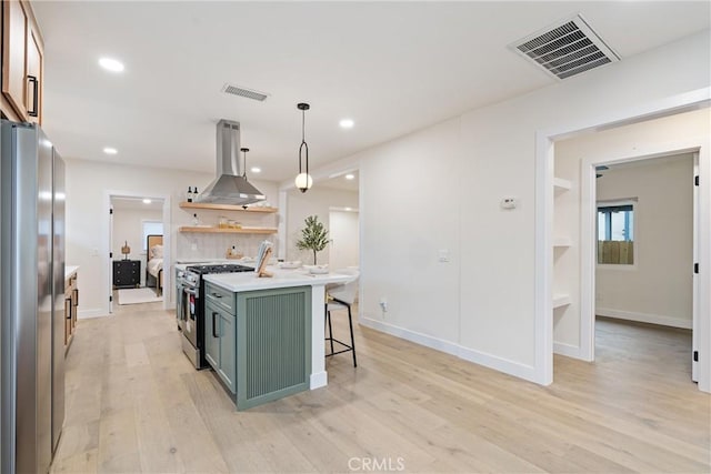 kitchen with island range hood, green cabinets, visible vents, and appliances with stainless steel finishes