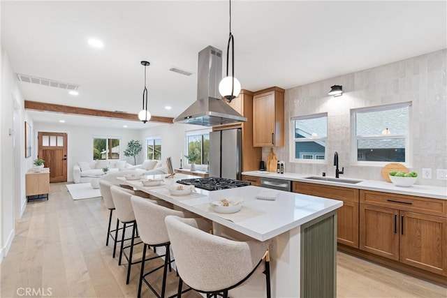 kitchen with island exhaust hood, a sink, visible vents, appliances with stainless steel finishes, and recessed lighting