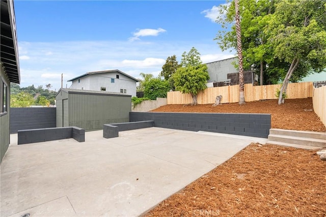 view of patio featuring a storage shed, an outdoor structure, and a fenced backyard