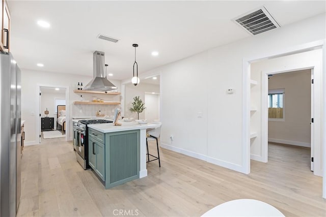 kitchen with green cabinetry, visible vents, appliances with stainless steel finishes, and island range hood