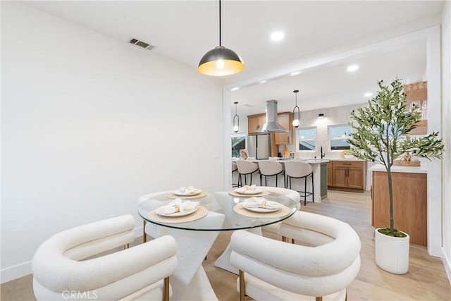 dining room featuring light wood-type flooring, baseboards, visible vents, and recessed lighting