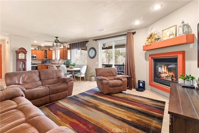 living area featuring light tile patterned flooring, visible vents, recessed lighting, ceiling fan, and a glass covered fireplace