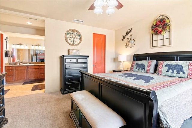 bedroom with light colored carpet, ensuite bathroom, a ceiling fan, and visible vents