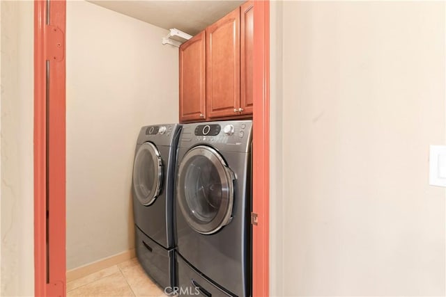laundry area featuring cabinet space, baseboards, light tile patterned floors, and washer and dryer