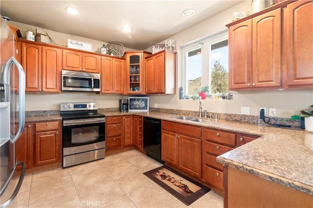 kitchen featuring a sink, stainless steel appliances, brown cabinets, recessed lighting, and glass insert cabinets