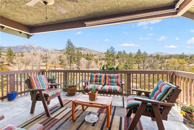 balcony featuring a mountain view, a ceiling fan, and an outdoor living space