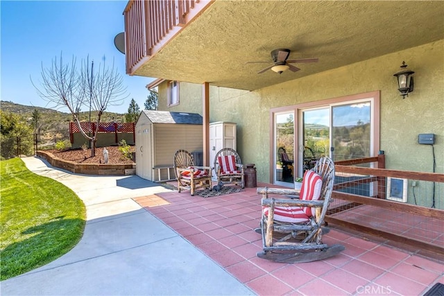 view of patio featuring fence, an outdoor structure, a ceiling fan, and a shed