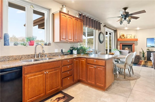 kitchen with a ceiling fan, a sink, dishwasher, a warm lit fireplace, and light tile patterned flooring