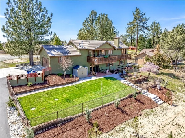 rear view of house featuring a vegetable garden, an outdoor structure, a wooden deck, a fenced backyard, and a storage unit