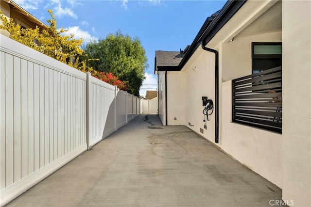 view of side of property featuring stucco siding, fence, and a patio area
