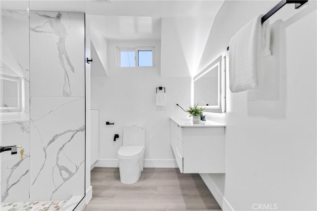 full bathroom with toilet, a marble finish shower, wood finished floors, baseboards, and vanity