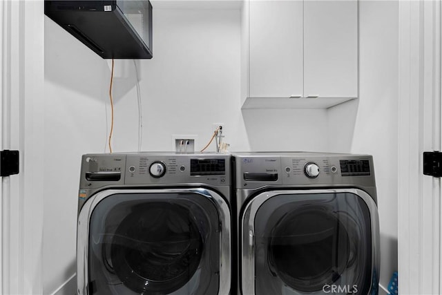 clothes washing area with washing machine and dryer and cabinet space