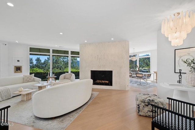 living room featuring a large fireplace, wood finished floors, an inviting chandelier, and recessed lighting