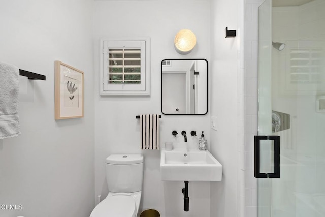 bathroom featuring a stall shower, toilet, and a sink