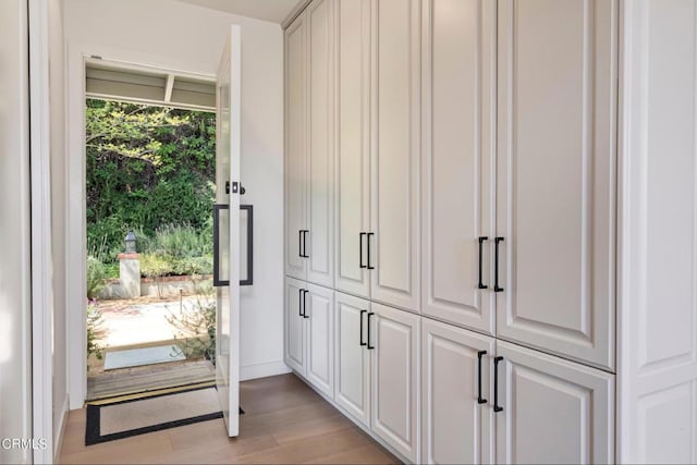doorway with baseboards and light wood finished floors