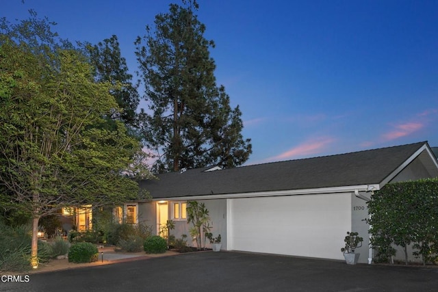 ranch-style house featuring stucco siding, driveway, and a garage