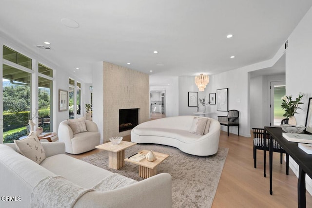living area with recessed lighting, visible vents, a chandelier, light wood-style floors, and a large fireplace
