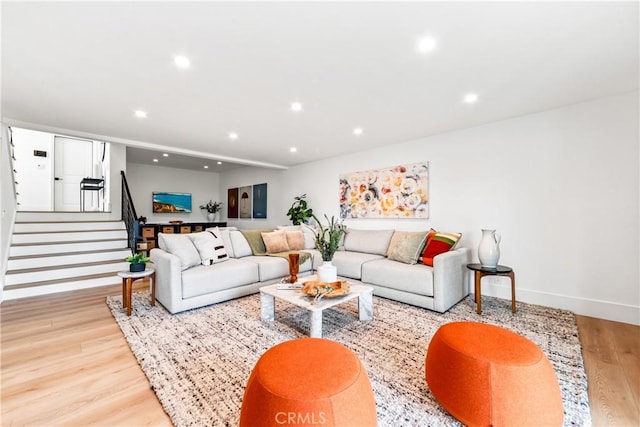 living room featuring stairs, wood finished floors, baseboards, and recessed lighting