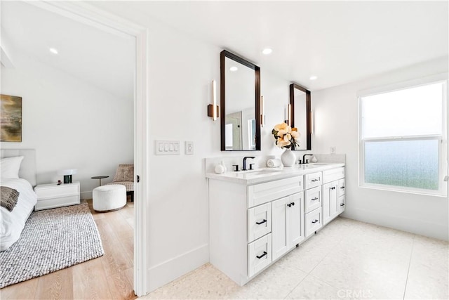 bathroom with baseboards, recessed lighting, double vanity, and a sink