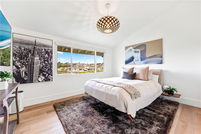 bedroom featuring lofted ceiling, baseboards, and wood finished floors